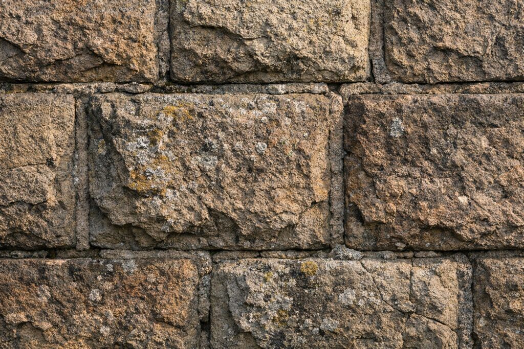 Nahaufnahme einer Mauer aus Buckelquadern mit Randschlag, Flechten und feinen Rissen