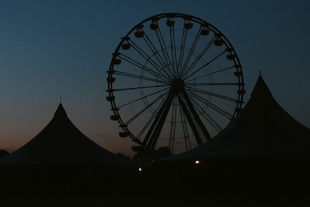 Silhouette eines Riesenrads über Festzelten in der Abenddämmerung