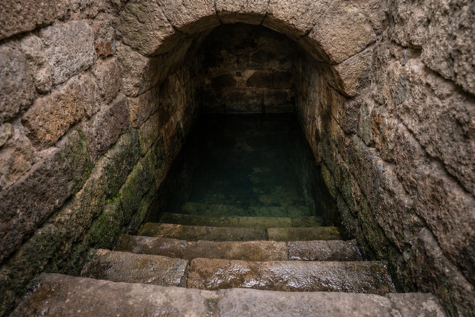 Schacht eines mittelalterlichen Ritualbads mit Steintreppe hinab zum Wasser